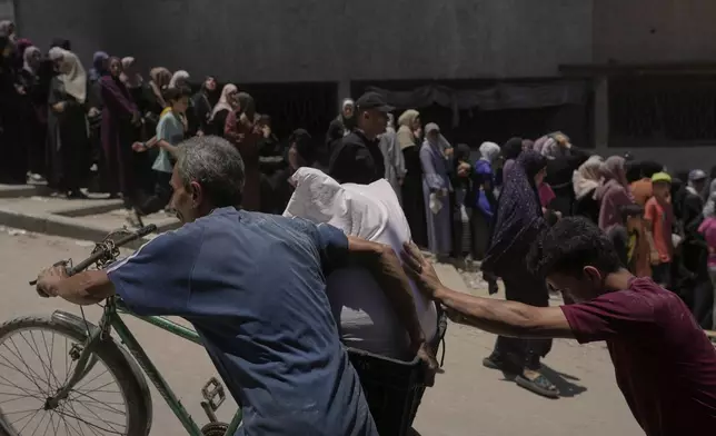 Palestinians carry bags of flour distributed by the World Food Programme (WFP) in Gaza City, northern Gaza Strip, Saturday, July 12, 2025. (AP Photo/Jehad Alshrafi)