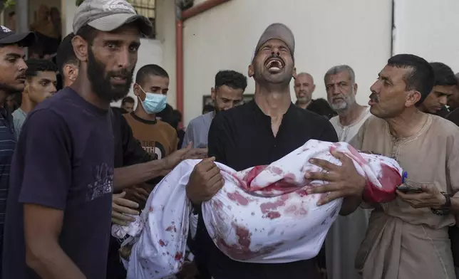 A Palestinian man carries the body of his child, who was killed in an Israeli military airstrike on Gaza, at Shifa Hospital in Gaza City, Saturday, July 12, 2025. (AP Photo/Jehad Alshrafi)