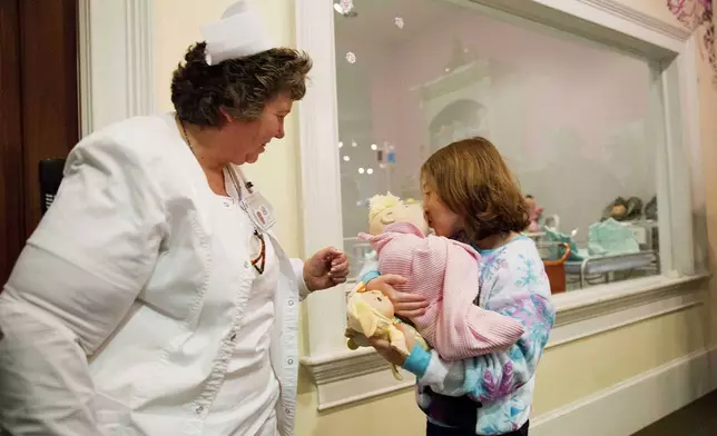 FILE - Talon Shaffer, right, kisses a Cabbage Patch Kid after it was delivered by Cyndi Pappadouplos, a "licensed patch nurse" at Babyland General Hospital, the birthplace of Cabbage Patch Kids, in Cleveland, Ga., on Nov. 21, 2014. (AP Photo/David Goldman, File)
