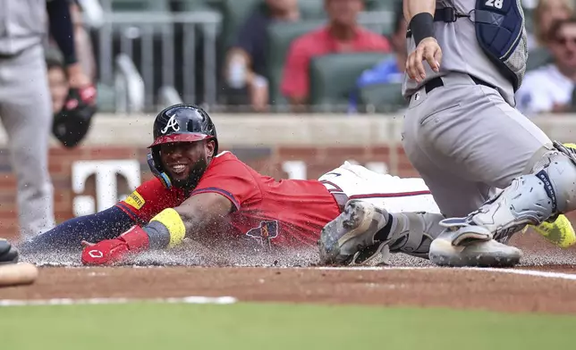 Atlanta Braves' Jurickson Profar, left, slides home ahead of a tag from New York Yankees catcher Austin Wells (28) in the first inning of a baseball game, Friday, July 18, 2025, in Atlanta. (AP Photo/Colin Hubbard)