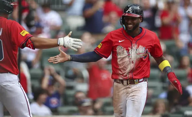 Atlanta Braves' Jurickson Profar, right, reacts after scoring a run in the first inning of a baseball game against the New York Yankees, Friday, July 18, 2025, in Atlanta. (AP Photo/Colin Hubbard)