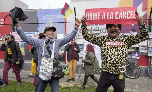 An opponent of former President Alvaro Uribe displays a sign reading in Spanish "Uribe to jail" outside the court where a verdict is expected in his trial for witness tampering in Bogota, Colombia, Monday, July 28, 2025. (AP Photo/Fernando Vergara)