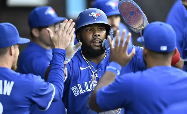 Toronto Blue Jays' Vladimir Guerrero Jr. celebrates with teammates in the dugout after scoring on a Bo Bichette single during the fourth inning of a baseball game against the Chicago White Sox, Monday, July 7, 2025, in Chicago. (AP Photo/Paul Beaty)