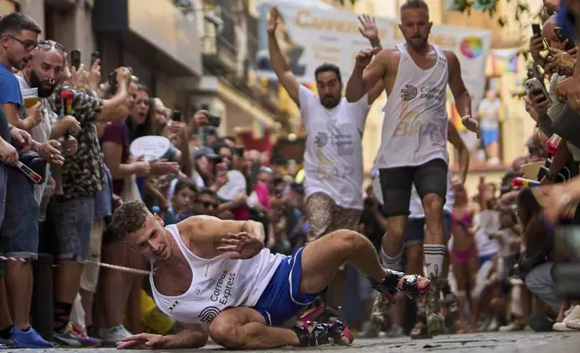 A participant falls wearing shoes with heels of at least 15 centimeters (5.9 inches) as they compete in the annual high heel race during Madrid's Pride week in Madrid, Spain, Thursday, July 3, 2025. (AP Photo/Manu Fernandez)