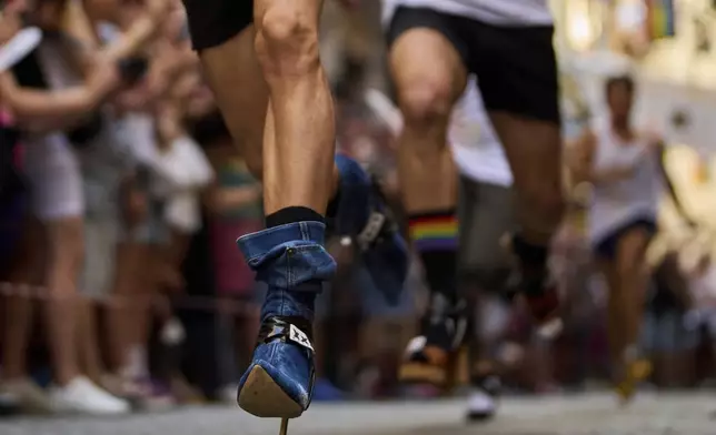 Participants wearing shoes with heels of at least 15 centimeters (5.9 inches) compete in the annual high heel race during Madrid's Pride week, in Madrid, Spain, Thursday, July 3, 2025. (AP Photo/Manu Fernandez)