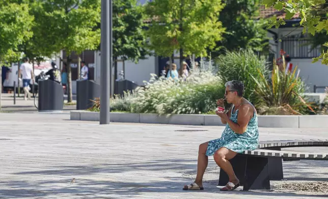 A woman eats an ice cream, Monday, June 30, 2025 in Saint-Jean-de-Luz, southwestern France. (AP Photo/Nicolas Mollo)