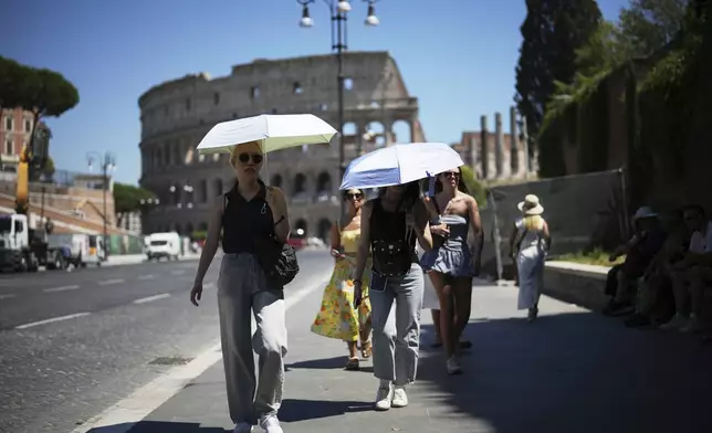 People use umbrellas in hot weather to shelter from the sun while walking past the Colosseum, in Rome, Monday, June 30, 2025. (AP Photo/Andrew Medichini)