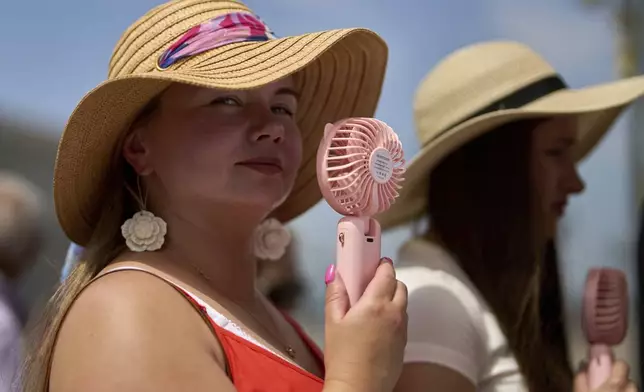 A woman cools herself with a handheld electric fan during a heat wave in Madrid, Spain, Tuesday, July 1, 2025. (AP Photo/Manu Fernandez)