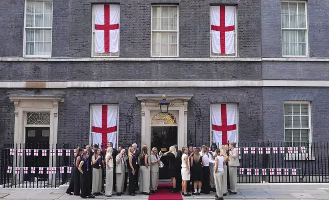 England head coach Sarina Wiegman, holding the trophy, and the players arrive for a special reception, to celebrate their victory in the Women's Euro 2025 final, at Downing Street in London, Monday, July 28, 2025.(AP Photo/Kirsty Wigglesworth)