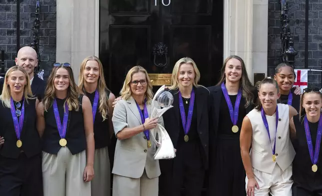 England head coach Sarina Wiegman holds the trophy posing with the players upon arriving for a special reception, to celebrate their victory in the Women's Euro 2025 final, at Downing Street in London, Monday, July 28, 2025.(AP Photo/Kirsty Wigglesworth)
