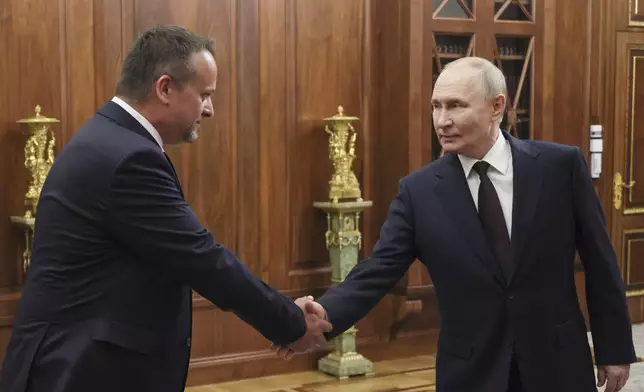 Russian President Vladimir Putin, right, shakes hands with a newly appointed acting Transport Minister Andrey Nikitin during their meeting at the Kremlin in Moscow, Russia, Monday, July 7, 2025. (Mikhail Metzel, Sputnik, Kremlin Pool Photo via AP)