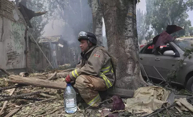 A rescue worker rests as others put out a fire of a building destroyed by a Russian drone strike in Zaporizhzhia, Ukraine, on Monday, July 7, 2025. (AP Photo/Kateryna Klochko)