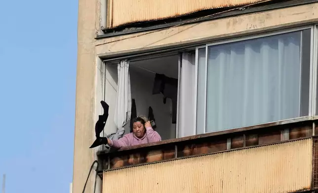 A woman signals for help inside a building on fire in Santiago, Chile, Thursday, July 10, 2025. (AP Photo/Esteban Felix)