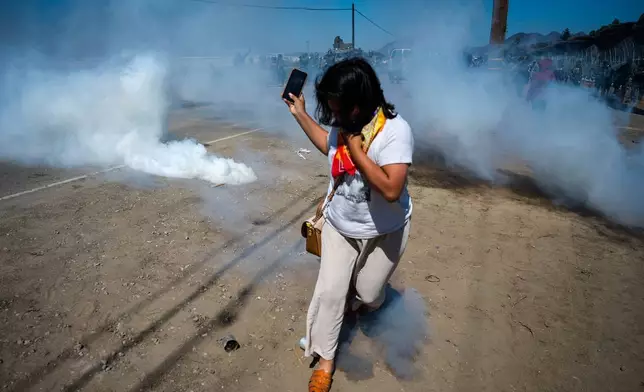 A protester runs from tear gas fired by federal immigration agents to clear a path for vehicles during a raid in an agricultural region of Camarillo, Calif., Thursday, July 10, 2025. (AP Photo/Michael Owen Baker)