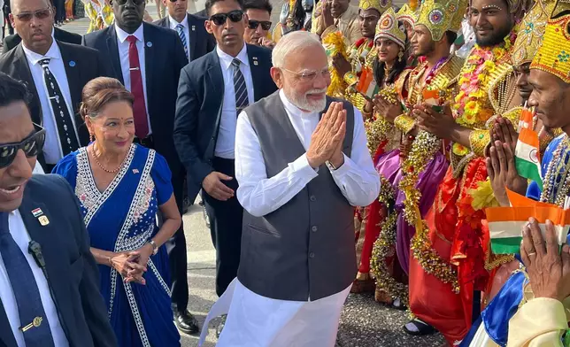 India's Prime Minister Narendra Modi greets people alongside Trinidad and Tobago's Prime Minister Kamla Persad-Bissessar, left, dressed in traditional Indian, at Piarco International Airport in Piarco, Trinidad and Tobago, Thursday, July 3, 2025. (AP Photo/Jermaine Cruickshank)
