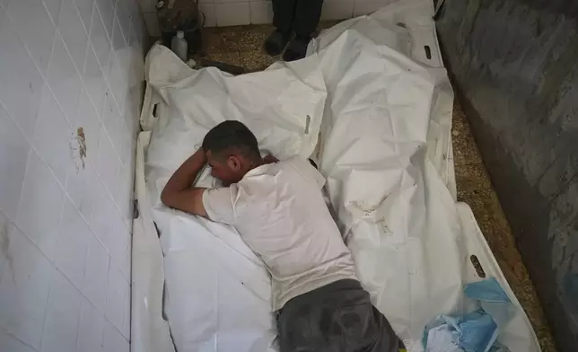 Youssef Abd Rabbo cries over the body of his mother, Manal Abd Rabbo, who was among 10 people, including two women and five children, killed in an Israeli strike while they were waiting to receive nutritional supplements at a Project Hope-run medical clinic in Deir al-Balah, Gaza Strip, Thursday, July 10, 2025. (AP Photo/Abdel Kareem Hana)