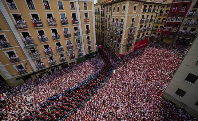 A municipal music band makes its way through the crowd as revelers pack the main square during the start of nine days of uninterrupted partying in Pamplona's famed running-of-the-bulls festival in Pamplona, Spain, Sunday, July 6, 2025. (AP Photo/Miguel Oses)