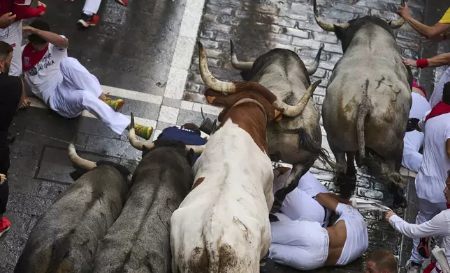 Revelers run alongside José Escolar Gil's fighting bulls during the sixth running of the bulls at the San Fermín Festival in Pamplona, Spain, Saturday, July 12, 2025. (AP Photo/Miguel Oses)