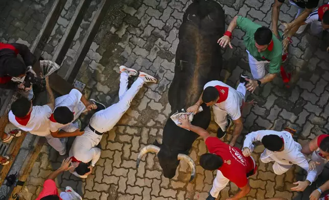 Revelers run alongside Jandilla's fighting bulls during the fifth running of the bulls at the San Fermín Festival in Pamplona, Spain, Friday, July 11, 2025. (AP Photo/Miguel Oses)