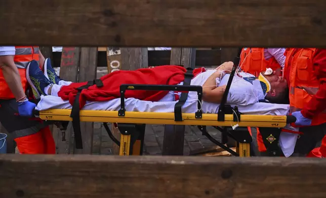 A runner who was injured during the running of the bulls is carried on a stretcher by a medical team at the San Fermín Festival in Pamplona, Spain, Thursday, July 10, 2025. (AP Photo/Miguel Oses)