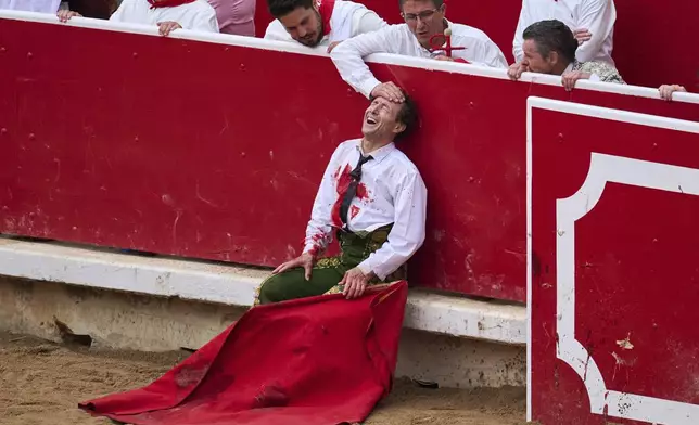 Spanish bullfighter Rafaelillo grimaces in pain after being gored by a bull during a bullfight at the San Fermín festival in Pamplona, northern Spain, Saturday, July 12, 2025. (AP Photo/Miguel Oses)