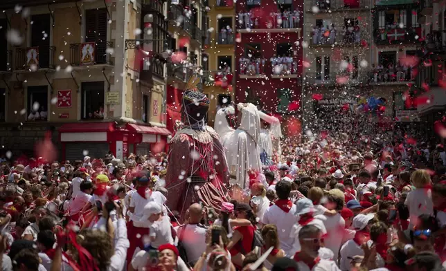 Revelers gather during a performance by a troupe of giants and bigheads at the San Fermín festival in Pamplona, northern Spain, Monday, July 14, 2025. (AP Photo/Miguel Oses)