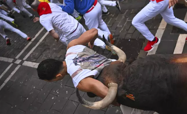 Revelers run with bulls from Cebada Gago ranch during the second day of the running of the bulls at the San FermÌn fiestas in Pamplona, Spain, Tuesday, July 8, 2025. (AP Photo/Miguel Oses)