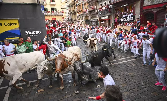 Revelers run with bulls from Cebada Gago ranch during the second day of the running of the bulls at the San FermÌn fiestas in Pamplona, Spain, Tuesday, July 8, 2025. (AP Photo/Miguel Oses)