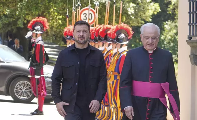 Ukraine President Volodymyr Zelenskyy, left, walks with Father Lorenzo Sapienza past Swiss guards ahead of his meeting with Pope Leo XIV in Castel Gandolfo, Italy, Wednesday, July 9, 2025. (AP Photo/Gregorio Borgia)