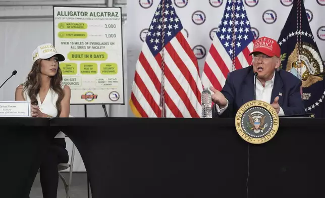 President Donald Trump speaks during a roundtable at "Alligator Alcatraz," a new migrant detention facility at Dade-Collier Training and Transition facility, Tuesday, July 1, 2025, in Ochopee, Fla., as Homeland Security Secretary Kristi Noem, looks on. (AP Photo/Evan Vucci)