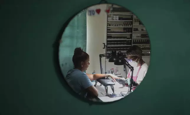Manicurist Dayana Roche works on a client's nails at her home-run nail salon in Havana, Cuba, Thursday, June 26, 2025. (AP Photo/Ramon Espinosa)
