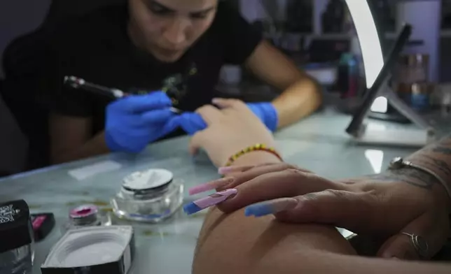 Manicurist Marisel Darias Valdes works on a client's nails at a salon she has set up in her home, in Havana, Cuba, Tuesday, June 24, 2025. (AP Photo/Ramon Espinosa)