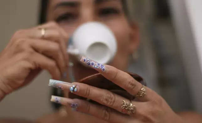 Yalema Gonzalez, wearing long, decorative nails, drinks her afternoon coffee at her home in La Gallega, Havana province, Cuba, Saturday, June 28, 2025. (AP Photo/Ramon Espinosa)
