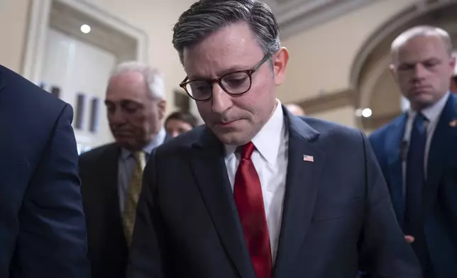 Speaker of the House Mike Johnson, R-La., walks behind his security detail through a crowd of reporters as he tries to push President Donald Trump's signature bill of tax breaks and spending cuts across the finish line even as conservative and moderate GOP holdouts slow that effort, at the Capitol in Washington, Wednesday, July 2, 2025. (AP Photo/J. Scott Applewhite)