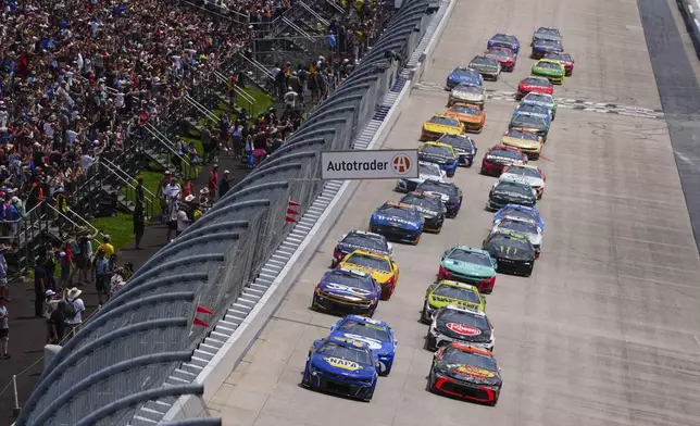 Chase Elliott (9) and Chase Briscoe (19) lead the field down the front stretch during a NASCAR Cup Series auto race at Dover Motor Speedway, Sunday, July 20, 2025, in Dover, Del. (AP Photo/Derik Hamilton)
