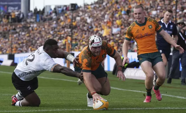 Australia's Fraser McReight, center, scores a try as Fiji's Josua Tuisova, left, comes in too late during their rugby union international match in Newcastle, Australia, Sunday, July 6, 2025. (AP Photo/Mark Baker)