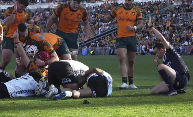 Australia's Harry Wilson, wearing a red helmet, celebrates scoring a try against Fiji during their rugby union international match in Newcastle, Australia, Sunday, July 6, 2025. (AP Photo/Mark Baker)