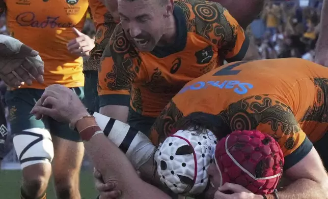 Australia's Harry Wilson, wearing a red helmet, celebrates with teammates after scoring a try against Fiji during their rugby union international match in Newcastle, Australia, Sunday, July 6, 2025. (AP Photo/Mark Baker)