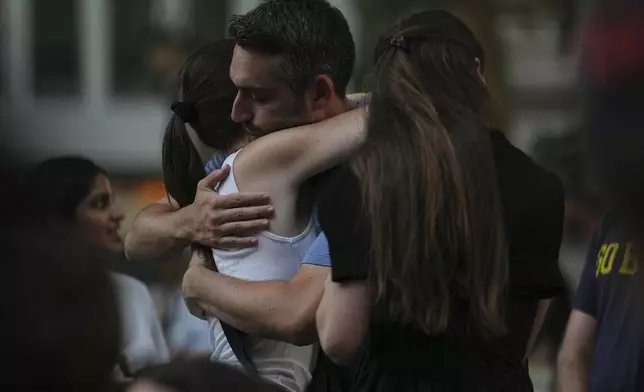 People hug while attending a vigil at Bryant Park for the people killed by a gunman at a Manhattan office building the day before, Tuesday, July 29, 2025, in New York. (AP Photo/Angelina Katsanis)