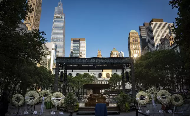 Flower wreaths with the words "Rest In Peace" stand at a vigil for the four people killed in the previous day's shooting at 345 Park Avenue, including NYPD officer Didarul Islam, in Bryant Park, Tuesday, July 29, 2025, in New York. (AP Photo/Angelina Katsanis)