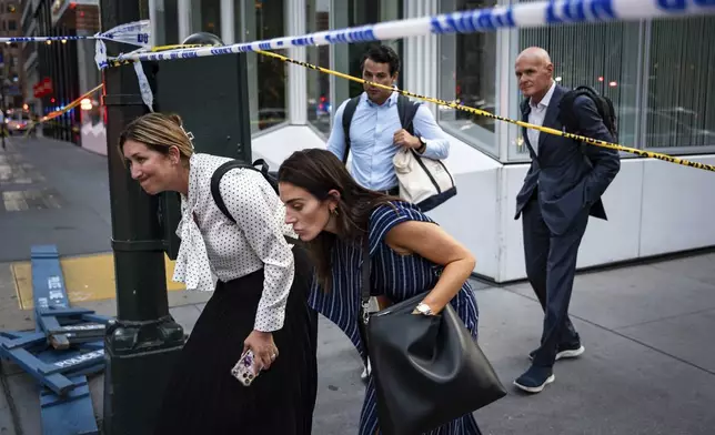 Pedestrians walk by police tape on the corner of Lexington Avenue and 53rd Street, near a Manhattan office building after a shooting, Monday, July 28, 2025, in New York. (AP Photo/Angelina Katsanis)