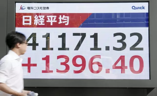 A person walks in front of an electronic stock board showing Japan's Nikkei index at a securities firm Wednesday, July 23, 2025, in Tokyo. (Kyodo News via AP)