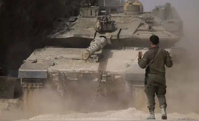 An Israeli soldier directs a tank at a staging area near the border with the Gaza Strip, in southern Israel, Tuesday, July 1, 2025. (AP Photo/Ariel Schalit)
