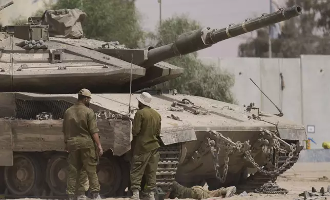 Israeli soldiers work on a tank at a staging area near the border with the Gaza Strip, in southern Israel, Tuesday, July 1, 2025. (AP Photo/Ariel Schalit)