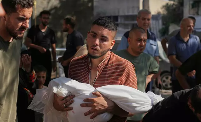 A man carries a child, who was killed in an Israeli strike, as he walks outside the Shifa Hospital, Gaza City, Monday, June 30, 2025. (AP Photo/Jehad Alshrafi)