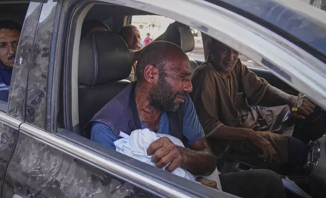 A man carries the wrapped body of a child killed in an Israeli strike that targeted a school in the northern Gaza Strip, as he arrives at Shifa Hospital. Friday, June 27, 2025, Gaza City. (AP Photo/Jehad Alshrafi)