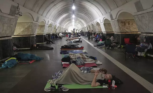 People rest in a metro station, being used as a bomb shelter, during a Russian attack in Kyiv, Ukraine, early Thursday, July 10, 2025. (AP Photo/Efrem Lukatsky)
