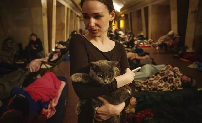 Maria, 25, holds a cat on the platform of a metro station as they take cover during a Russian attack on Kyiv, Ukraine, on Thursday, July 10, 2025. (AP Photo/Evgeniy Maloletka)
