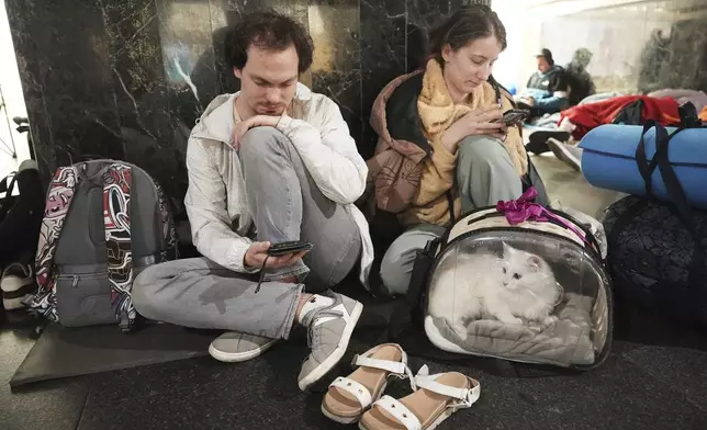 People rest in a metro station, being used as a bomb shelter, during a Russian attack in Kyiv, Ukraine, early Thursday, July 10, 2025. (AP Photo/Efrem Lukatsky)