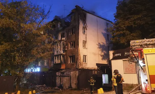 Firefighters stand near an apartment building destroyed after a Russian attack in Kyiv, Ukraine, early Thursday, July 10, 2025. (AP Photo/Efrem Lukatsky)